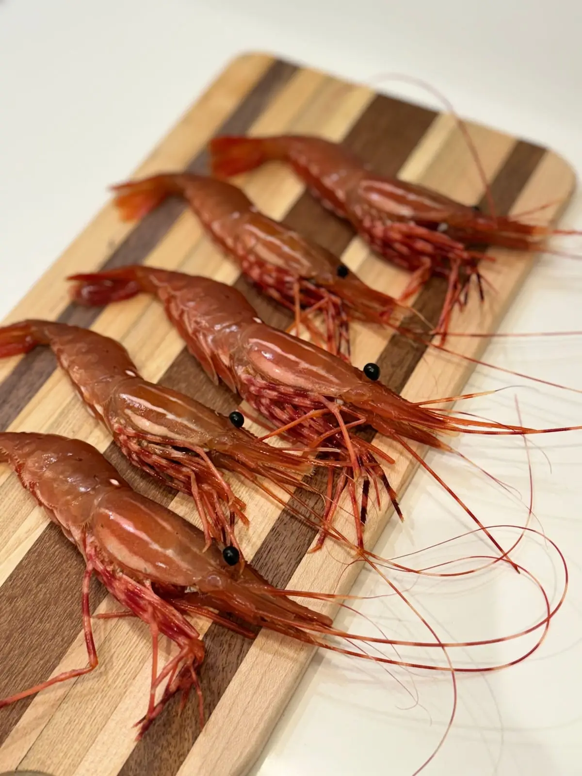 Whole BC spot prawns laid out on a wooden board