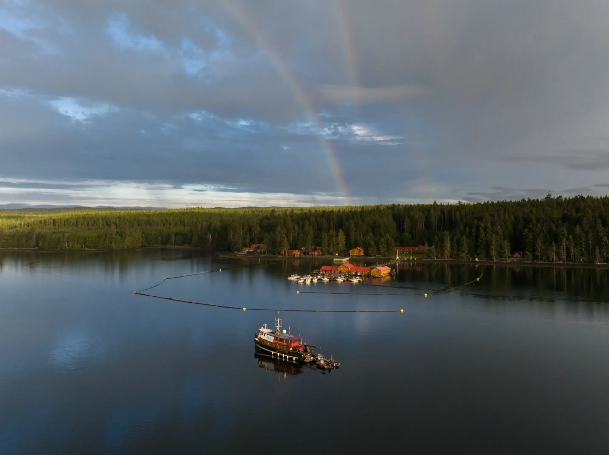 A fishing lodge on a calm northern BC bay beneath a rainbow