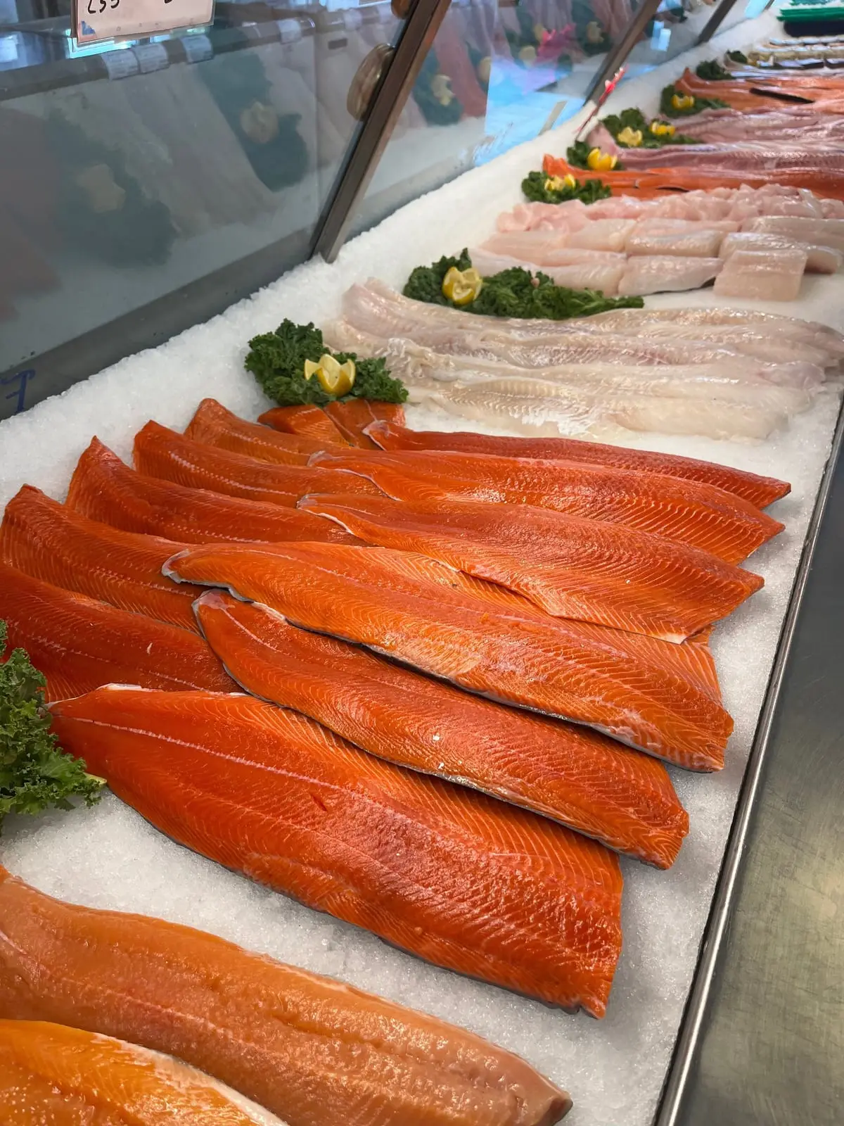 Salmon and white fish fillets on ice with lemon and kale