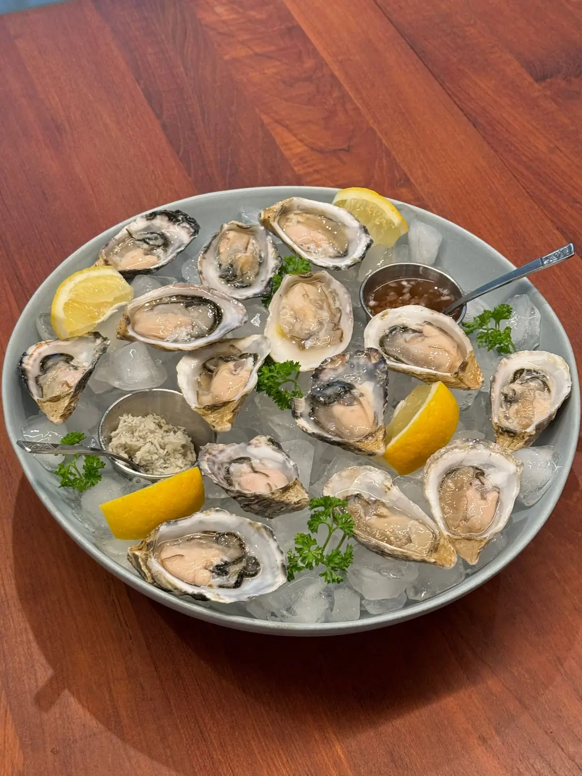 A platter of fresh oysters on the half shell over ice, with lemon and mignonette