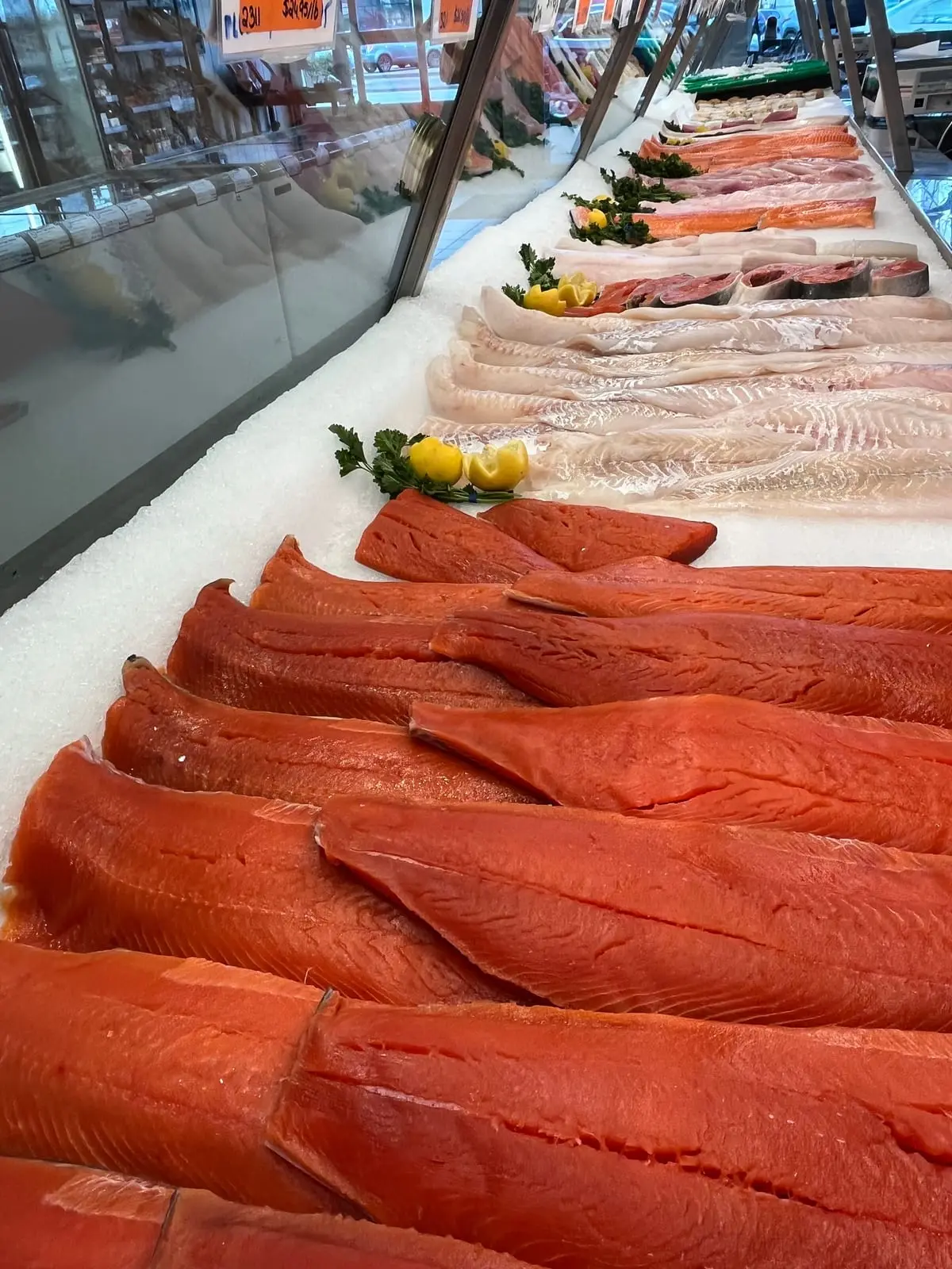 Rows of wild sockeye salmon fillets and white fish on ice in the seafood counter