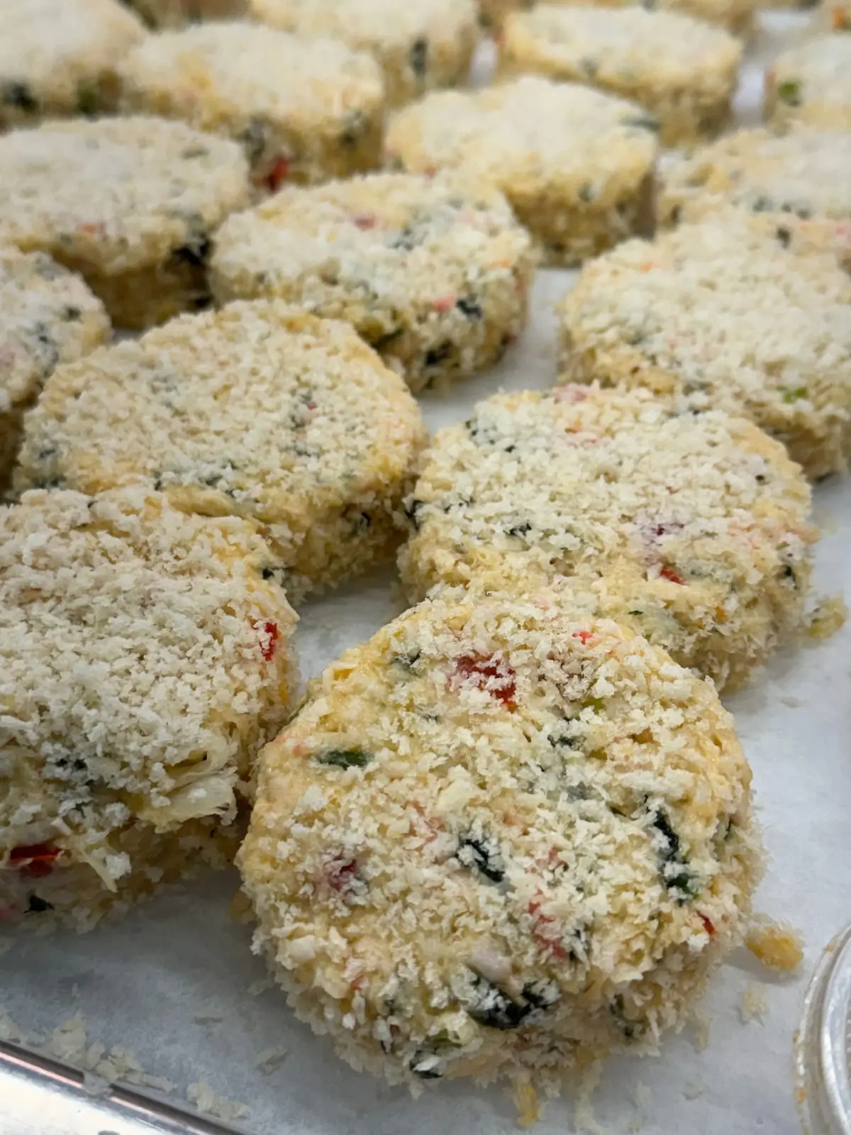 Hand-formed breaded crab cakes on parchment