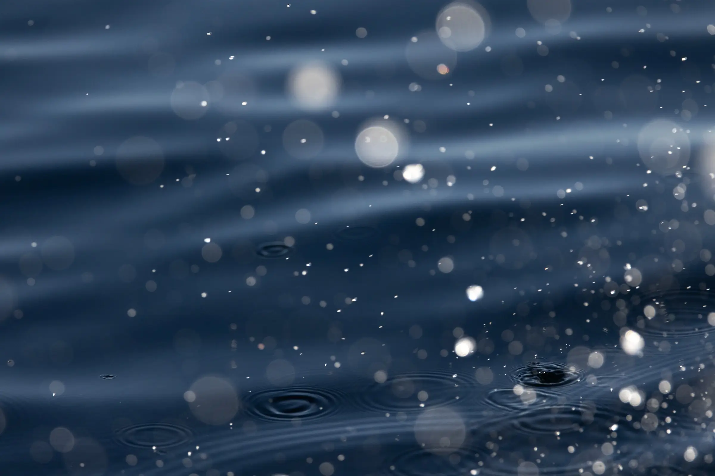 Droplets of sea spray caught in the light above dark blue ocean water