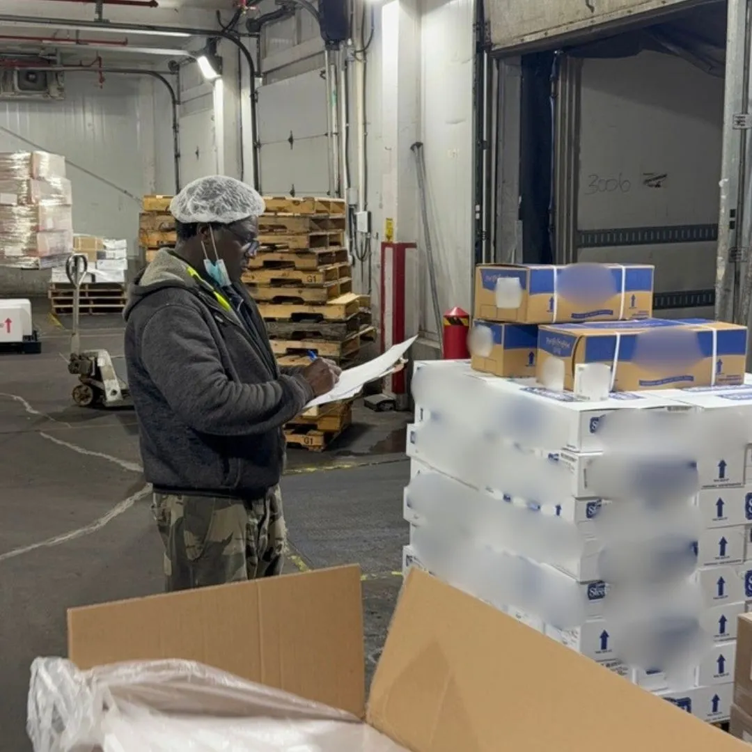 A receiver checking an inbound pallet of product against the paperwork at the receiving dock