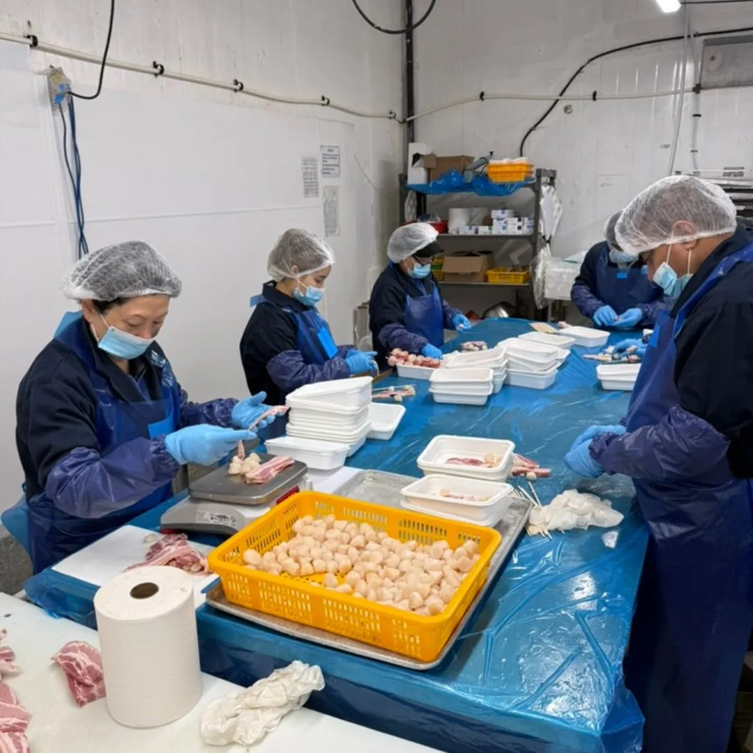 The team hand-wrapping scallops in bacon at the value-added production table