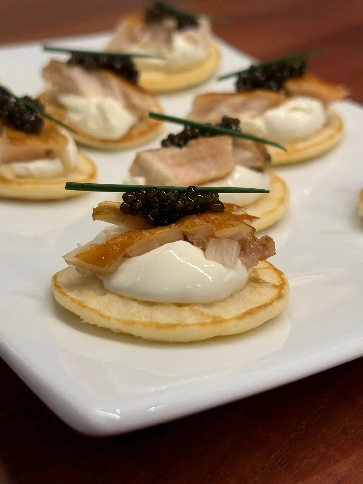 Blini canapés topped with crème fraîche, smoked fish and caviar