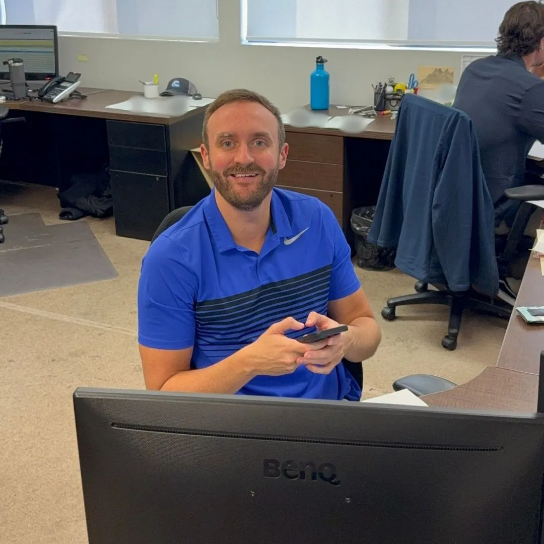 A team member smiling for the camera at a desk