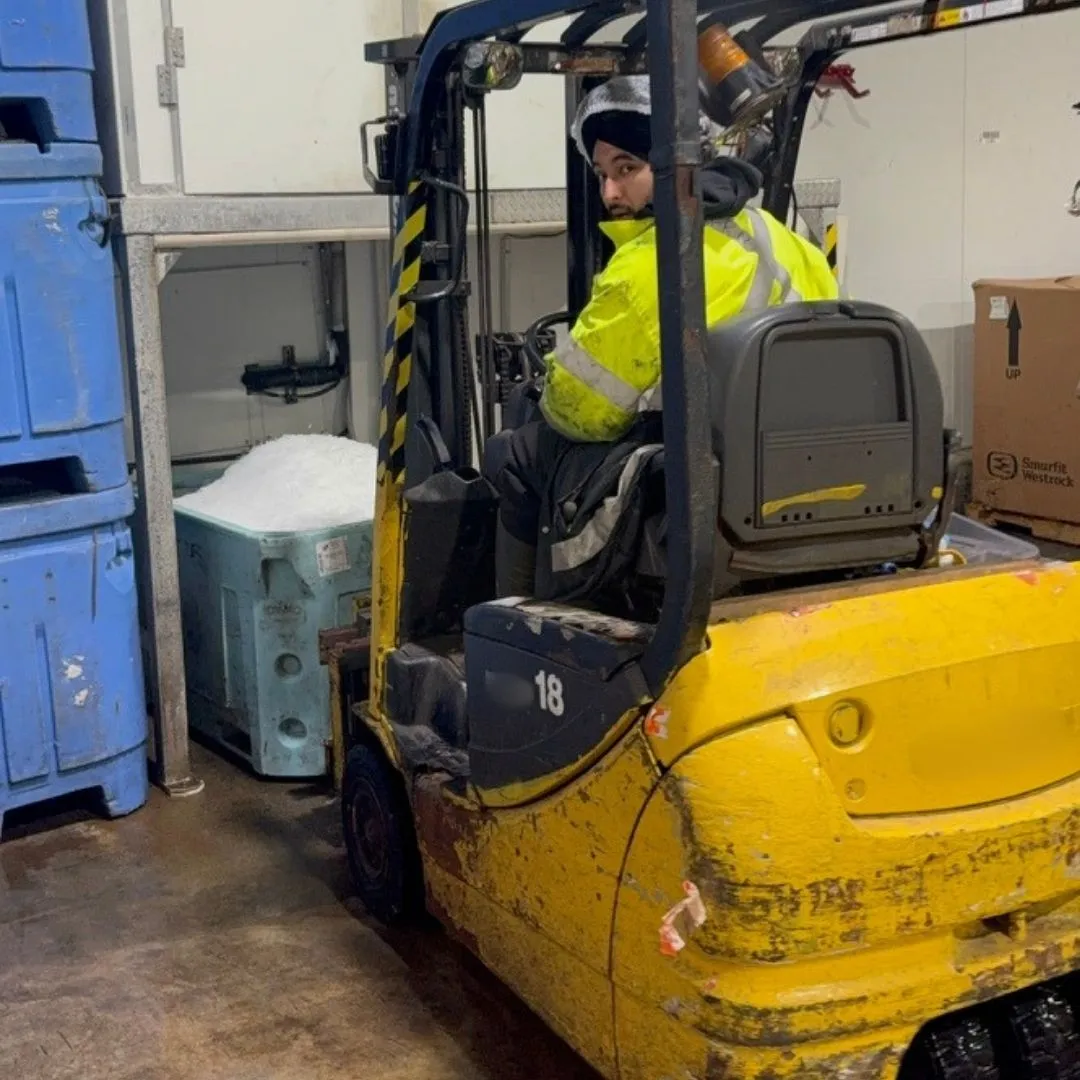 Forklift moving a tote of ice across the warehouse floor